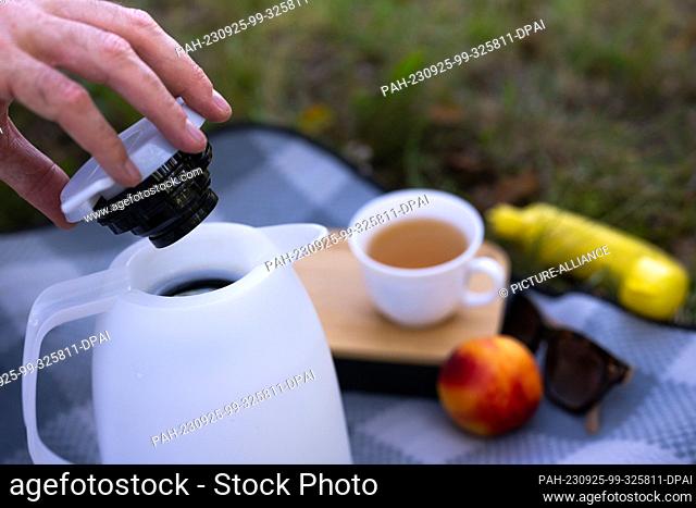 ILLUSTRATION - 17 September 2023, Berlin: A man opens the lid of a thermos of warm tea at a picnic. Photo: Monika Skolimowska/dpa