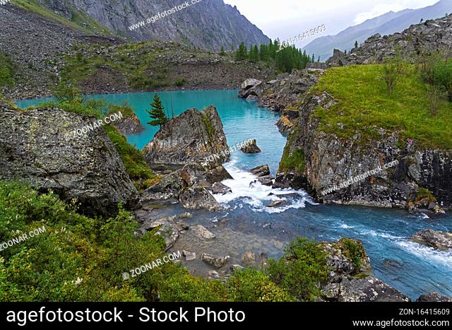Water flows over a small rapids between the two parts of the Upper Shavlinsky lake. August. Altai Mountains, Siberia, Russia