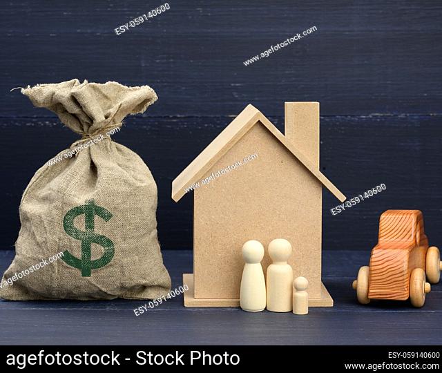 canvas bag full of money and a wooden house on a blue background. The concept of buying real estate, renting out. Profitable investment in real estate