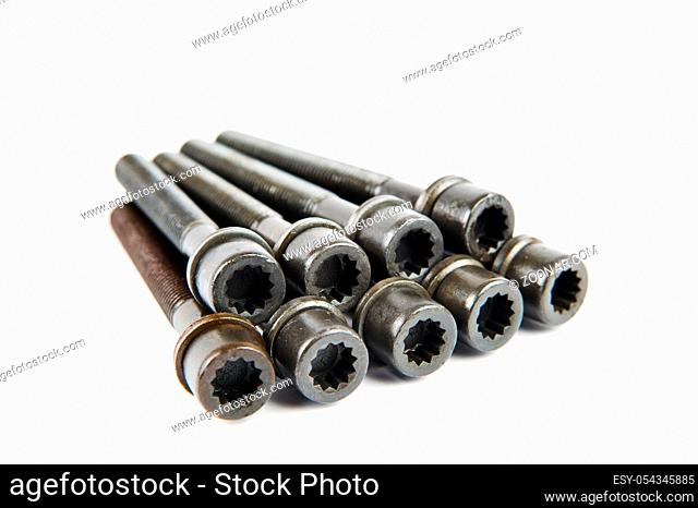 A set of new cylinder head bolts in oil on a white isolated background are shot in perspective at a wide angle. Spare parts for car repair