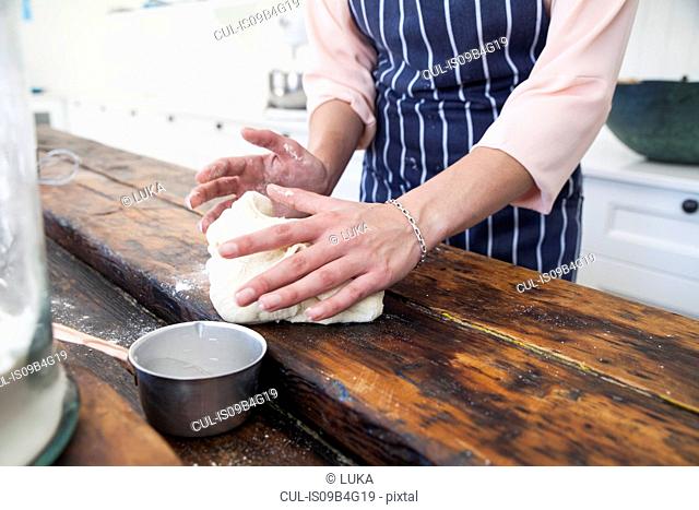 Cropped shot of young woman shaping dough at kitchen counter