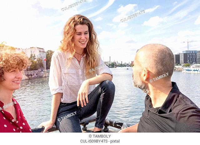 Man and female friends talking, river in background, Berlin, Germany