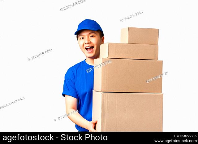 Online shopping, fast shipping concept. Friendly smiling young asian male courier in blue uniform carry boxes with orders