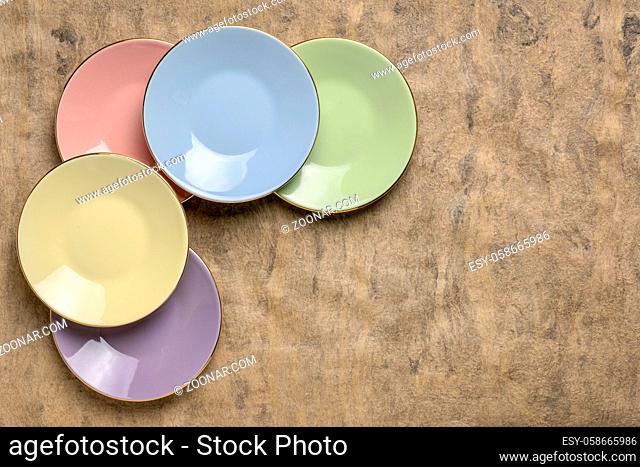 set of empty pastel porcelain saucers against handmade bark paper with a copy space