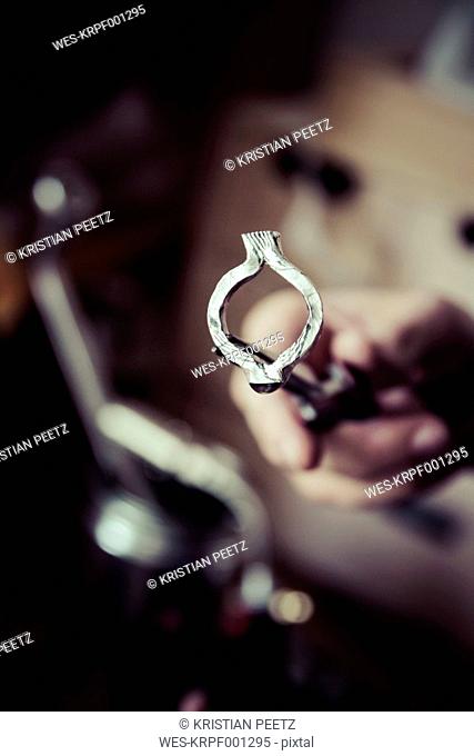 Goldsmith working on wedding rings in Mokume Gane style, hand holding unfinished ring