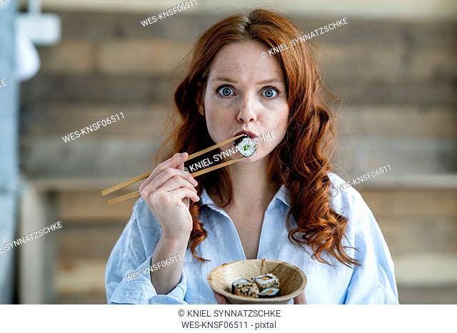 Portrait of redheaded woman eating sushi