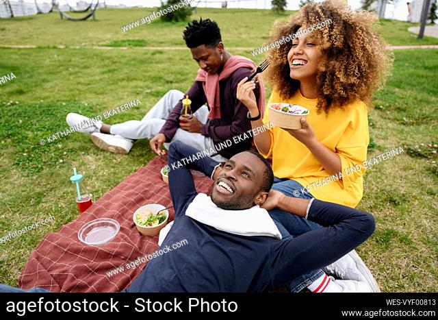 Woman eating lunch with friends in park at picnic