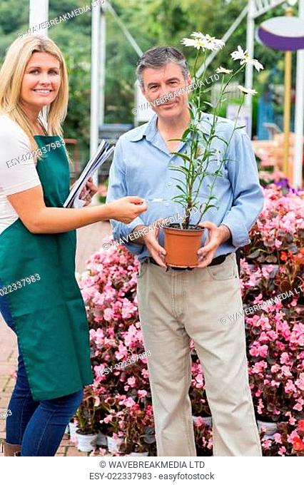 Florist giving advice to customer while smiling in garden center