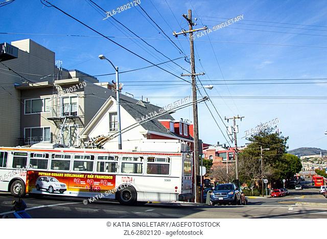 View of the streets in San Francisco at an intersection with city bus on a blue sky sunny day and sights of the mountains in the background