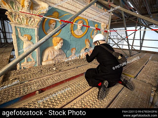 12 January 2022, Rhineland-Palatinate, Trier: A reporter films with her smatphone a part of the scaffolded 1:1 copy of the Unesco world heritage site Igeler...