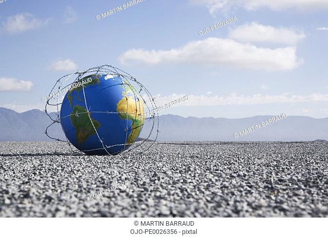 A globe entangled in barbed wire