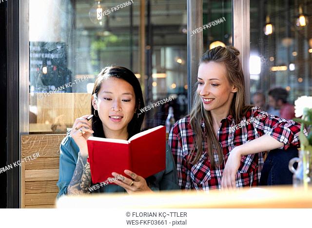Two women with book in a cafe