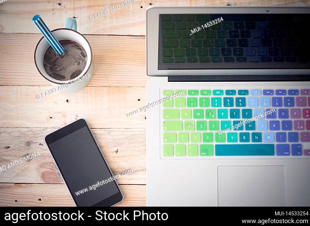 Top vertical view of desk with phone coffee and laptop. Work place on wooden table at office. Home and business online concept