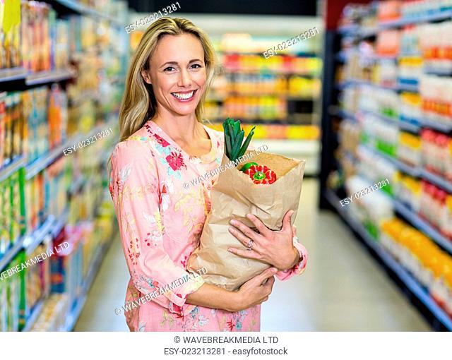 Pretty smiling woman holding grocery bag in the supermarket