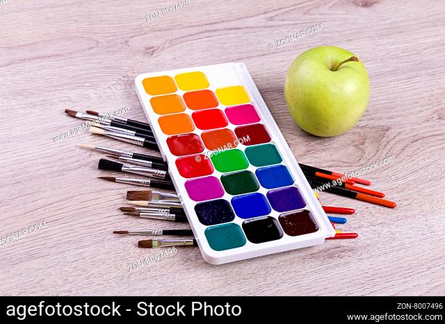 Watercolor paints with set of paint brushes on wooden background