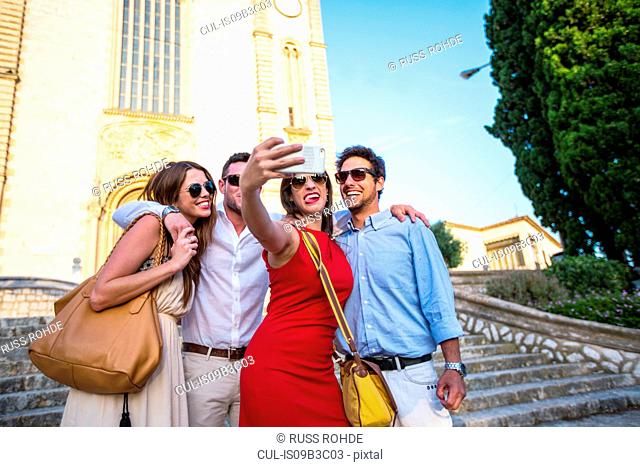 Two tourist couples taking selfie in front of church, Calvia, Majorca, Spain
