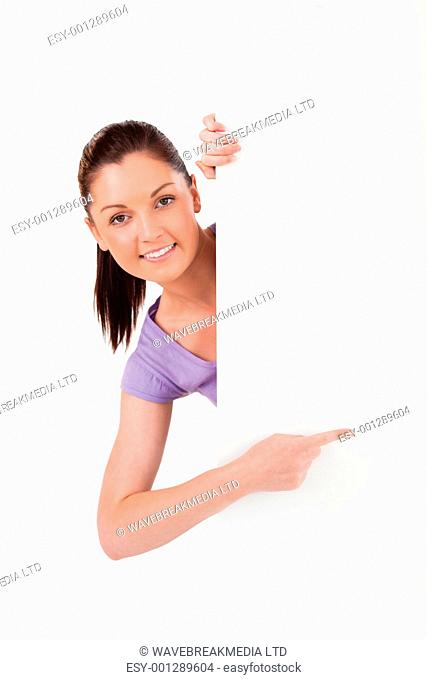 Charming female pointing at a copy space while standing against a white background