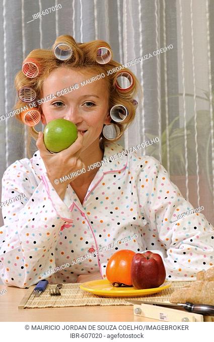 Redheaded woman with curlers in her hair eating breakfast