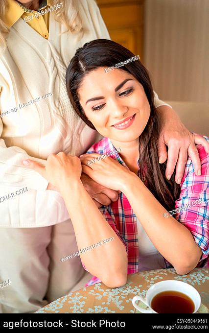 Attractive Young Girl Leans On Her Mother. Caring Hands Of Old Loving Mother Delicately Hug Daughter. Feeling Secure In Mother's Hands