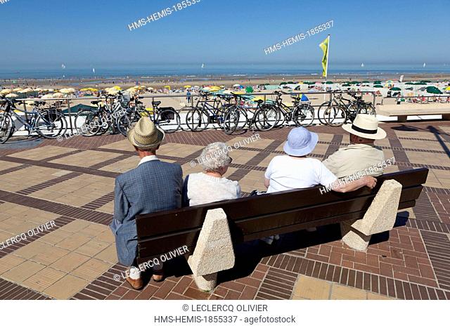 Belgium, West Flanders, De Haan, seniors sitting on a bench looking out to sea