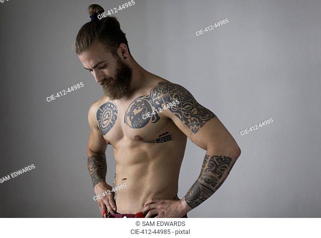 Portrait bare chested man with tattoos and beard