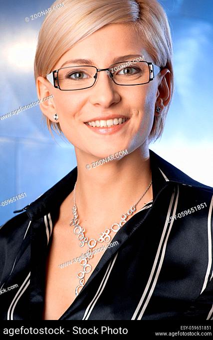 Indoor portrait of happy young businesswoman standing on office corridor, smiling