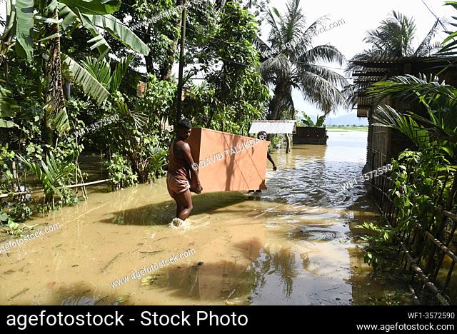 People carry belongings to safer place, from a flooded area in Dhekiabari village in Morigaon district of Assam, Monday, July 13, 2020