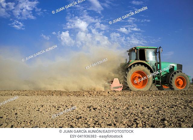 Farm tractor preparing dusty soil affected by drought. Drought and agriculture concept. Spain