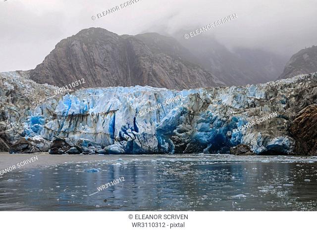 Blue ice face and floating ice, Sawyer Glacier and mountains, misty conditions, Stikine Icefield, Tracy Arm Fjord, Alaska, United States of America