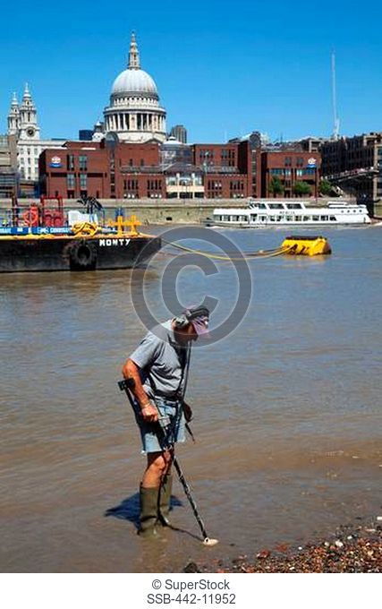UK, England, London, Southwark, Man metal detecting in River Thames