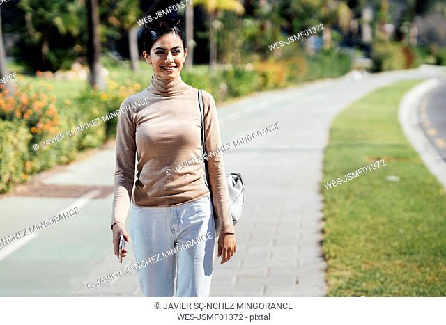 Smiling young woman walking on a path