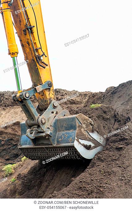Excavator digs up ground from sandy hill