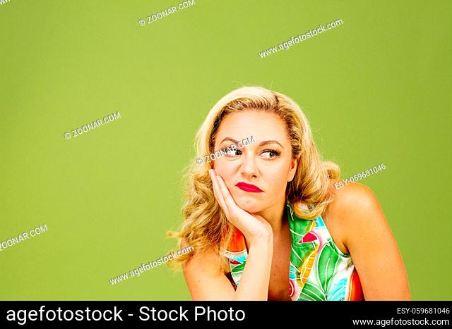 Portrait of an envious woman in bad mood looking right, isolated on green studio background