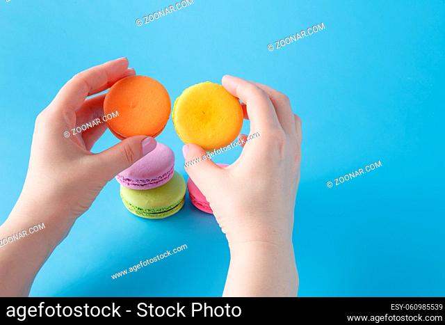 Macaroon in the hand on plain blue background