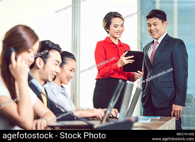 Young smiling businesswoman showing digital tablet to her colleague in the office