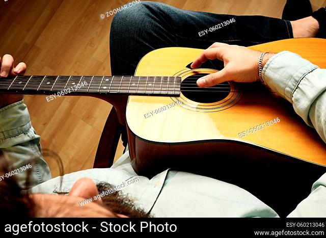 Cropped shot of man practicing in playing acoustic guitar. High quality photo