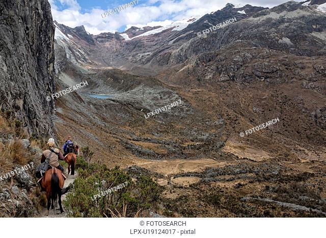 Mountain trail with riders on horseback, near Laguna 69 showing surrounding glaciers of Pisco East and Pisco West, and unnamed turquoise lake, valley below