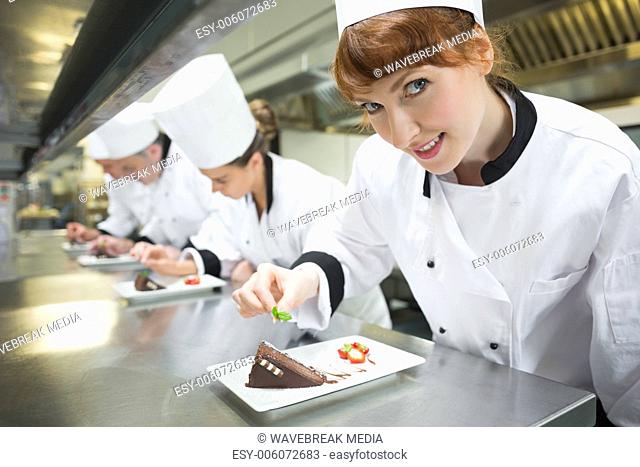 Smiling chef garnishing dessert plate