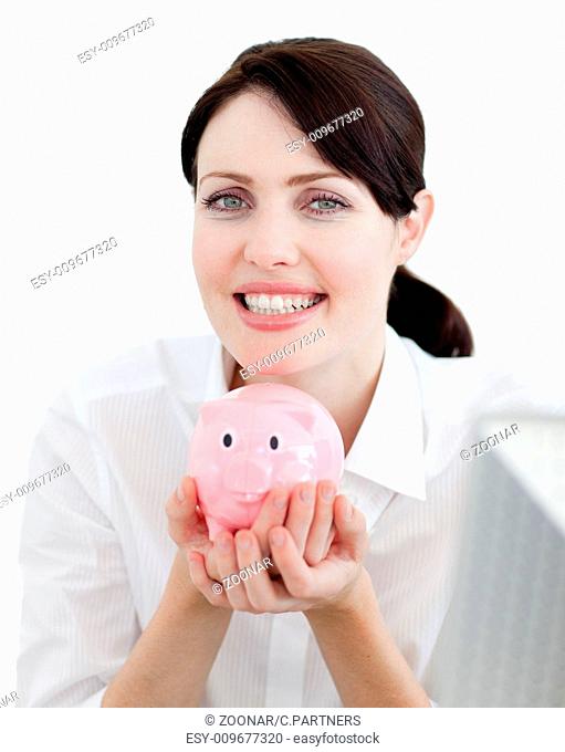 Businesswoman holding a piggybank against a white background smiling at the camera