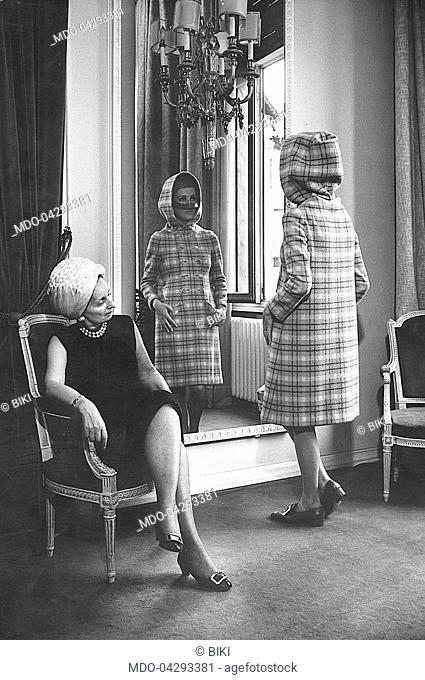 Italian fashion designer Biki (Elvira Leonardi Bouyeure) looking at a model wearing a winter coat in her atelier. Milan, July 1967