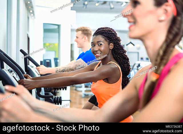 Beautiful woman smiling and looking at camera with confidence while running on treadmill in the gym