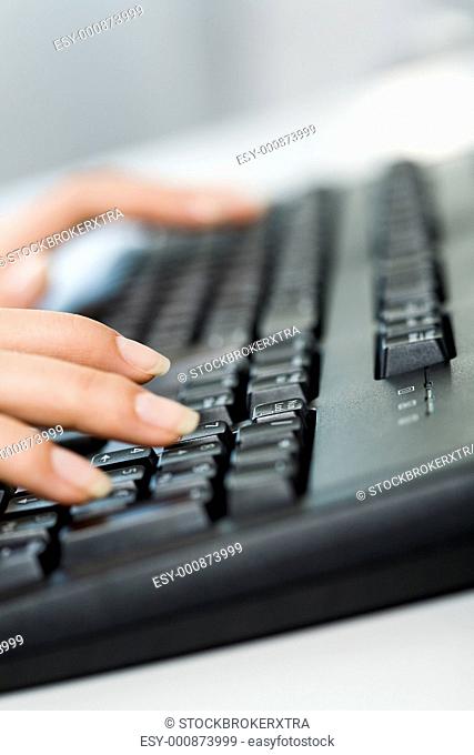 Close-up of female hands touching buttons of black keyboard