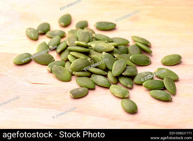 Green shelled pumpkin seeds on wooden background