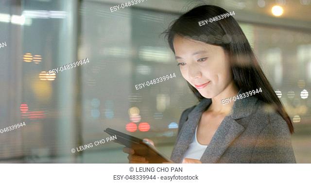 Window though Business woman using tablet computer at night