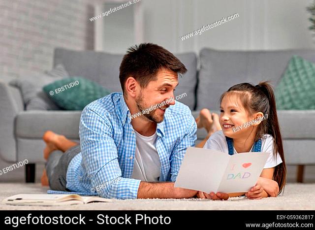 cute daughter giving father greeting card on holiday at home. Father's day