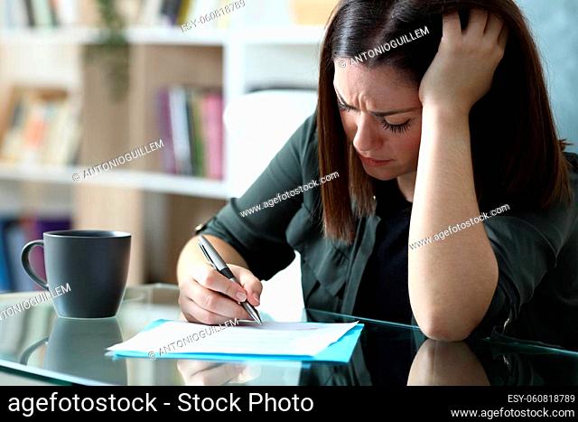 Sad woman sigining document complaining sitting in the living room at home