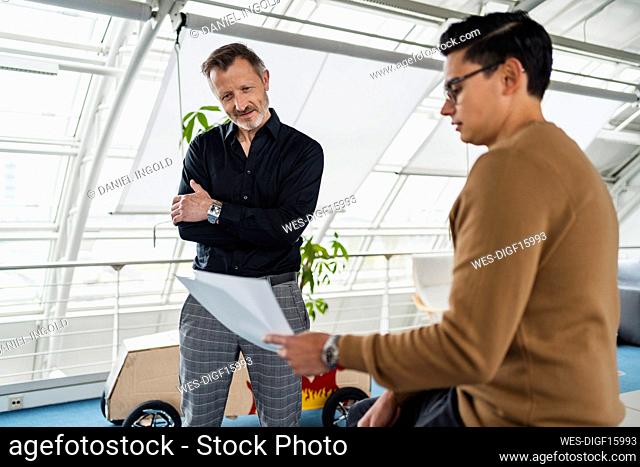 Businessman showing document to colleague while working in office