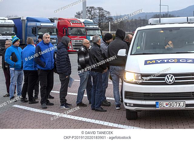 Truck drivers stand in line at the mobile ticket office (a van) for a new on-board unit of new Czech toll system, in Nachod, Czech Republic, on Monday