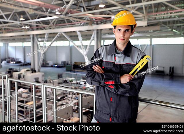 Portrait of a young worker with wrench at CNC factory