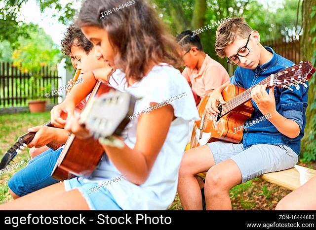 Gruppe Kinder im Gitarrenkurs übt das Gitarre spielen für die Talentshow im Ferienlager